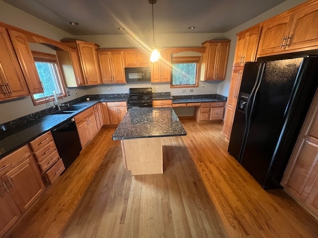 kitchen featuring light wood-type flooring, a kitchen island, a wealth of natural light, and black appliances