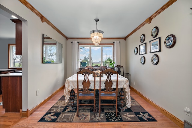 dining area featuring an inviting chandelier, light hardwood / wood-style flooring, and crown molding