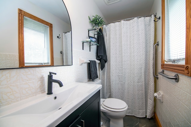 bathroom featuring vanity, tile walls, and toilet