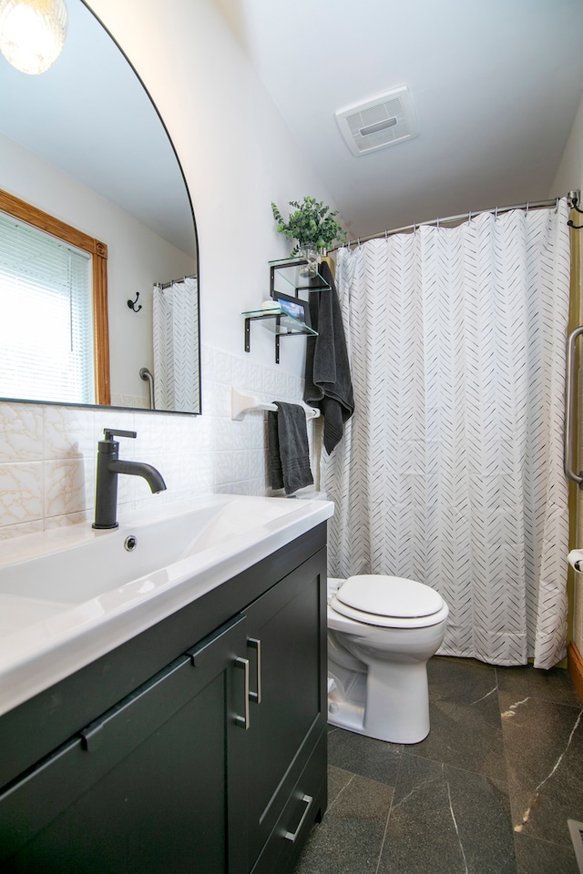 bathroom with vanity, toilet, tile walls, and tasteful backsplash