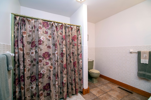 bathroom with toilet, tile patterned floors, tile walls, and curtained shower