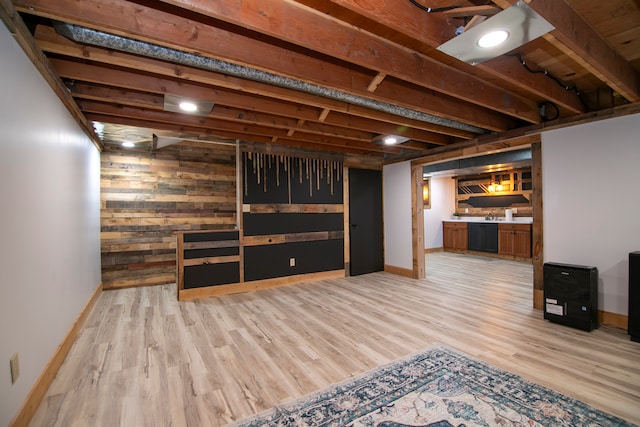 basement with light hardwood / wood-style flooring and wood walls