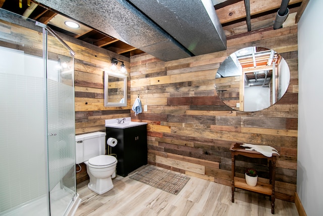 bathroom featuring hardwood / wood-style floors, vanity, wood walls, toilet, and walk in shower