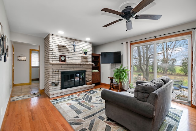 living room with hardwood / wood-style flooring, ceiling fan, and a fireplace