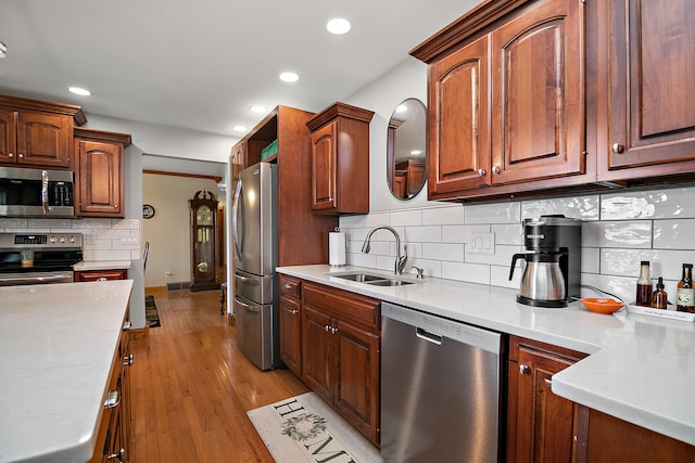 kitchen featuring sink, light wood-type flooring, stainless steel appliances, and tasteful backsplash