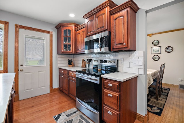 kitchen with decorative backsplash, stainless steel appliances, and light hardwood / wood-style floors