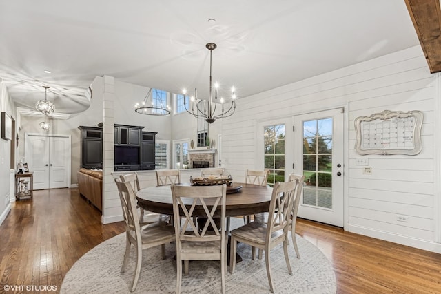 dining area with hardwood / wood-style floors, a fireplace, and a notable chandelier