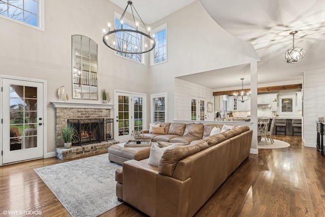 living room with an inviting chandelier, a fireplace, dark wood finished floors, and french doors