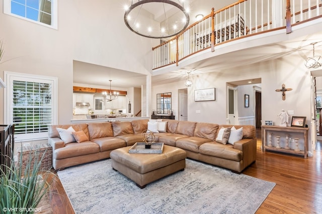 living area with a high ceiling, a notable chandelier, and wood finished floors