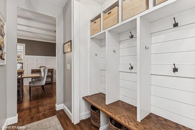 mudroom with ornamental molding, dark wood finished floors, and baseboards