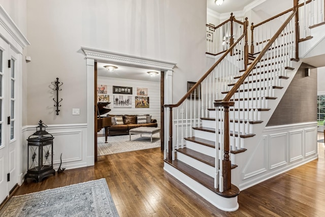 entryway with a high ceiling, crown molding, a decorative wall, and hardwood / wood-style floors