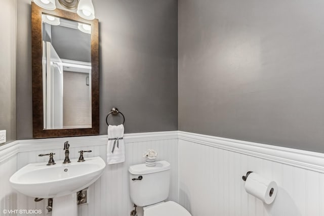 half bath featuring wainscoting, a sink, and toilet