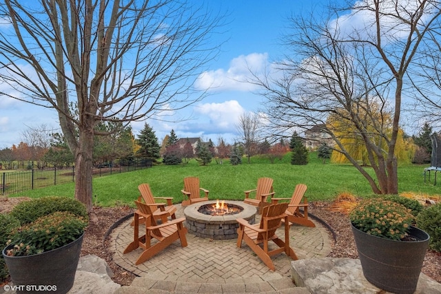 view of patio featuring a trampoline, fence, and a fire pit