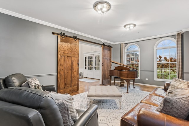 living room featuring wood finished floors, crown molding, baseboards, and a barn door