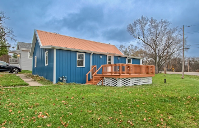 rear view of property featuring a lawn and a deck