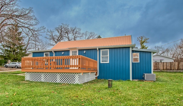 rear view of property with a lawn, central AC unit, and a wooden deck