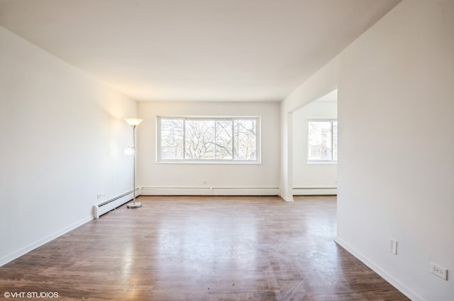 unfurnished room featuring a baseboard heating unit and hardwood / wood-style flooring