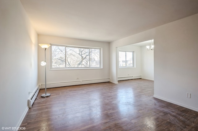 spare room featuring an inviting chandelier, a baseboard heating unit, and hardwood / wood-style flooring