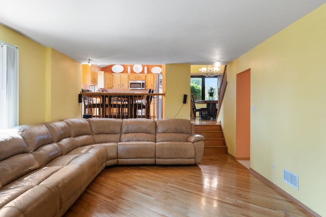 living room with light wood-type flooring and an inviting chandelier