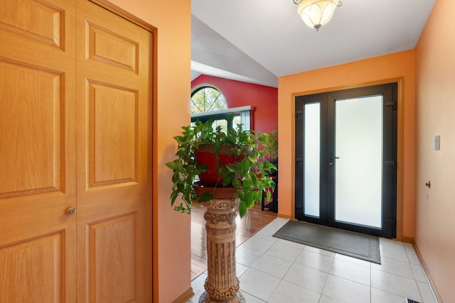 foyer entrance with light tile patterned floors and vaulted ceiling