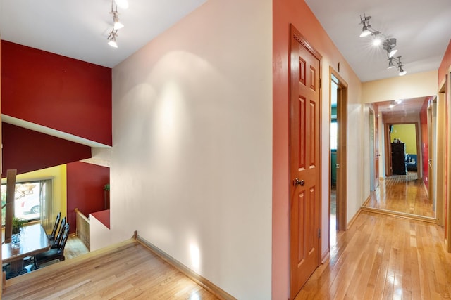 corridor with light hardwood / wood-style floors and track lighting