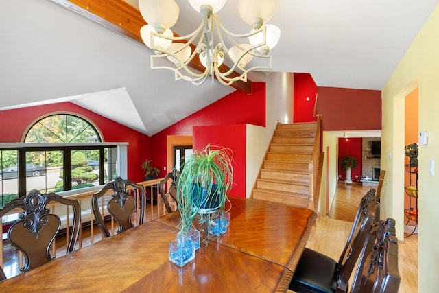 dining space with a chandelier, a brick fireplace, light wood-type flooring, and vaulted ceiling