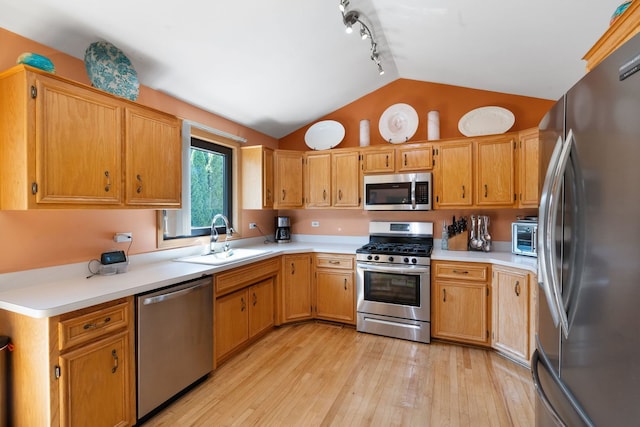 kitchen featuring light hardwood / wood-style floors, sink, appliances with stainless steel finishes, and vaulted ceiling