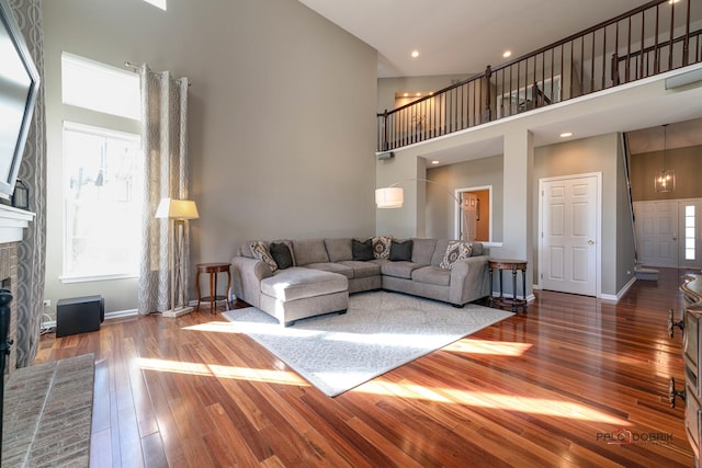 living room featuring a fireplace, a towering ceiling, and wood-type flooring