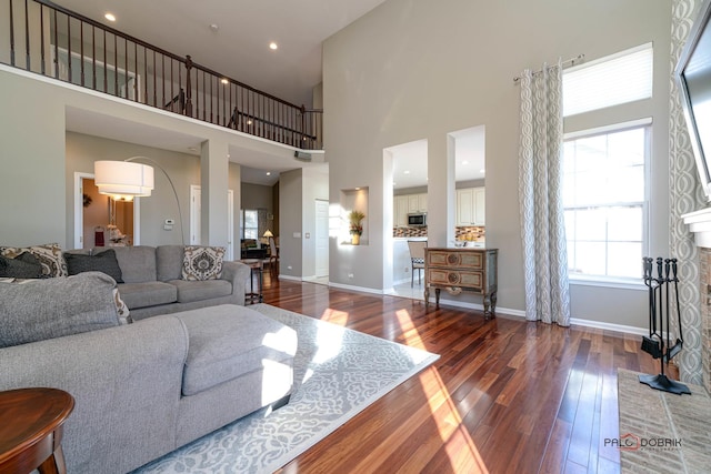 living room with a fireplace, wood-type flooring, and a towering ceiling