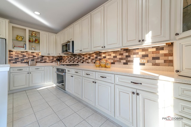 kitchen featuring backsplash, white cabinets, light tile patterned floors, and appliances with stainless steel finishes