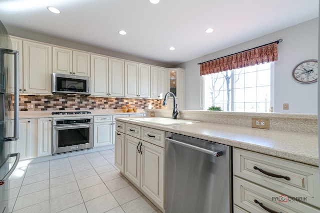 kitchen with light tile patterned flooring, appliances with stainless steel finishes, backsplash, and sink