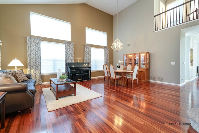 living room with high vaulted ceiling and dark wood-type flooring