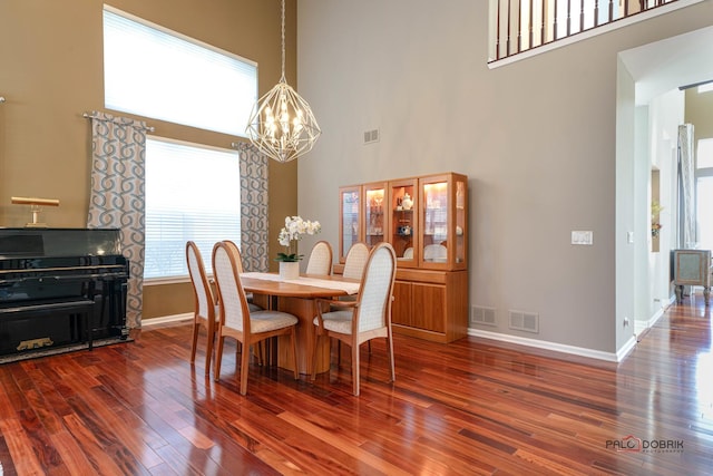 dining space featuring a towering ceiling, a chandelier, and dark hardwood / wood-style floors