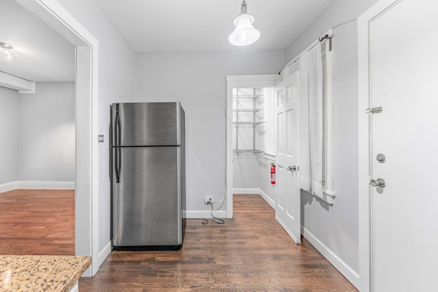 kitchen featuring pendant lighting, light stone countertops, dark wood-type flooring, and stainless steel refrigerator