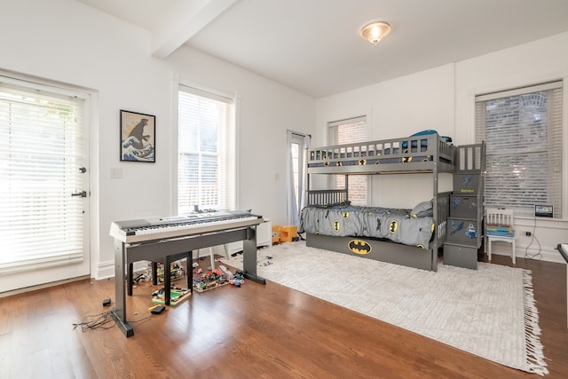 bedroom featuring beamed ceiling, hardwood / wood-style floors, and multiple windows