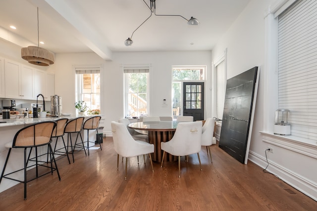 dining area with beam ceiling, plenty of natural light, and dark hardwood / wood-style floors