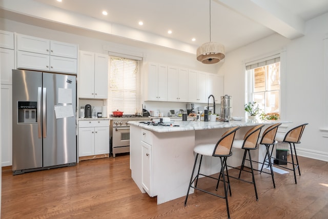 kitchen with white cabinets, a wealth of natural light, an island with sink, and appliances with stainless steel finishes