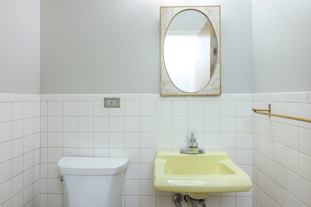 bathroom featuring sink, toilet, and tile walls