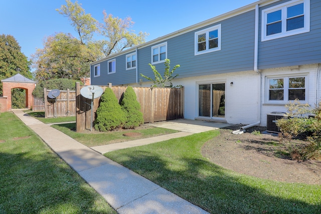 rear view of house with a gazebo, central air condition unit, and a lawn