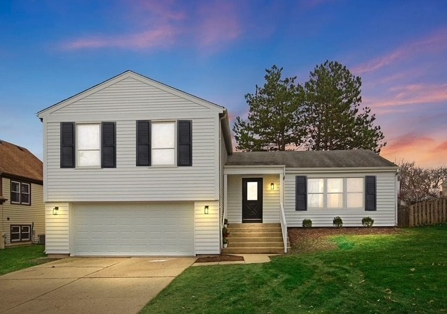 split level home featuring a garage and a yard