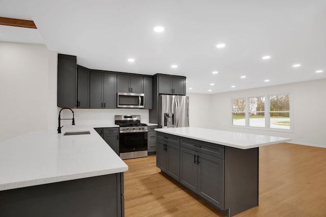 kitchen featuring light stone countertops, sink, a center island, light hardwood / wood-style flooring, and appliances with stainless steel finishes