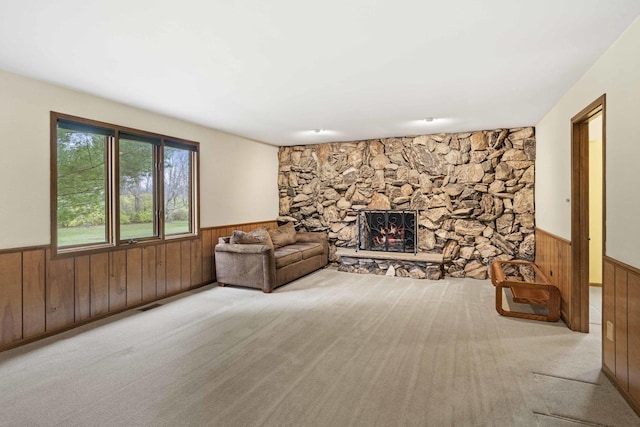 unfurnished living room featuring wood walls, light colored carpet, and a fireplace