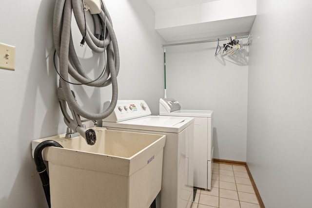 clothes washing area featuring washing machine and dryer, sink, and light tile patterned floors