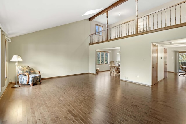 unfurnished living room featuring beamed ceiling, dark hardwood / wood-style floors, high vaulted ceiling, and a skylight