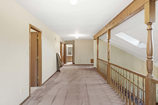 hallway featuring light carpet and lofted ceiling with skylight