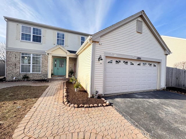 traditional-style home with a garage, fence, brick siding, and aphalt driveway