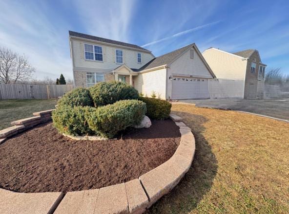 view of front of home with an attached garage, driveway, a front lawn, and fence