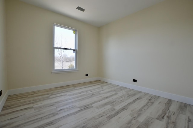 spare room with baseboards and wood finished floors