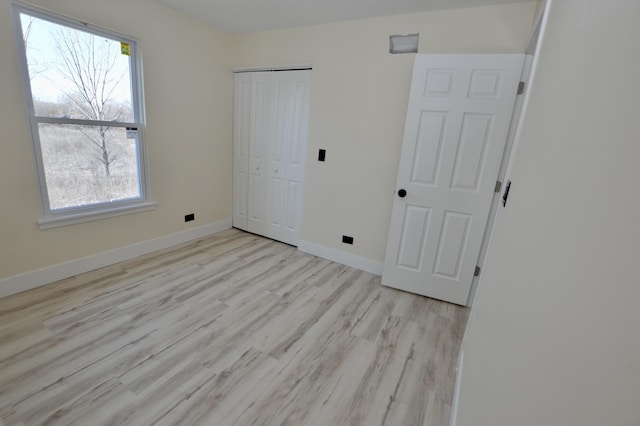 unfurnished bedroom featuring a closet, baseboards, and wood finished floors