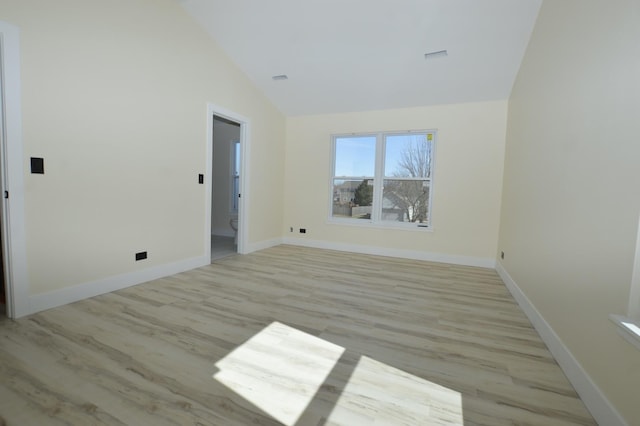 empty room with light wood-style flooring, baseboards, and high vaulted ceiling